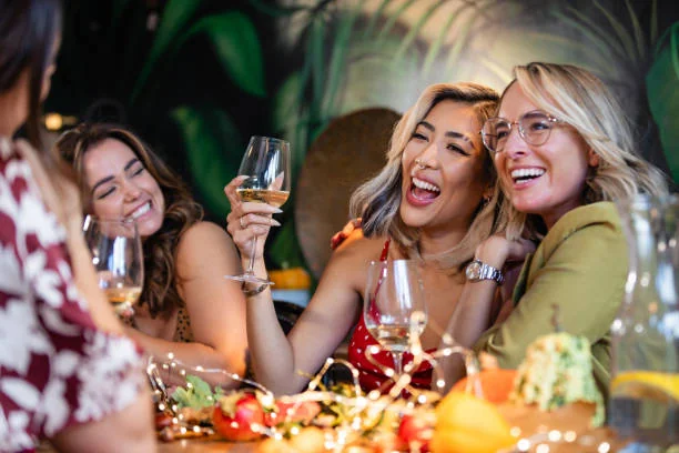 amies souriantes trinquant avec des verres de vin blanc pendant un brunch festif dans un restaurant a lille