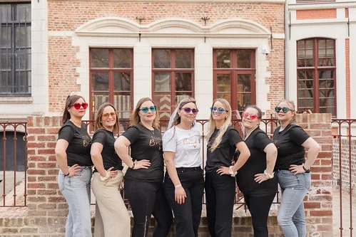 groupe de femmes portant des lunettes colorees posant ensemble lors dun evjf a lille devant un batiment en briques