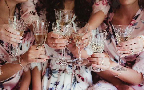 mains de femmes portant des robes fleuries trinquant au champagne lors d un evjf a paris