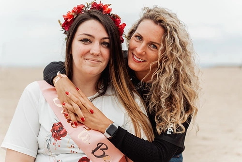 future mariee avec couronne de fleurs et amie l enlaçant sur la plage lors d un evjf meilleurs gages et defis evjf