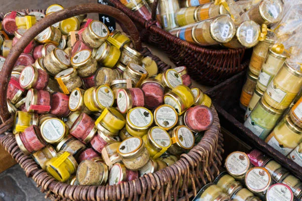 Pots de moutarde artisanale sur un marché local à Dijon, symbole de la gastronomie bourguignonne et des 10 endroits où sortir à Dijon pendant un EVJF.