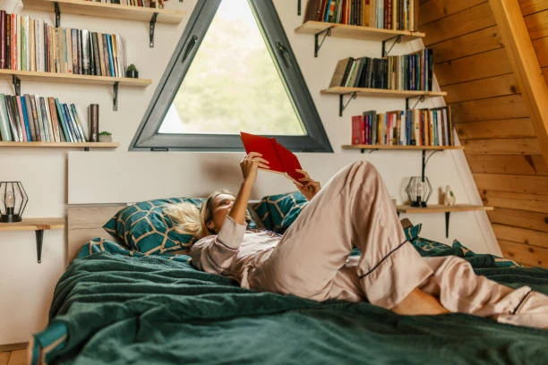 Femme lisant dans une chambre cosy en bois à Dijon, illustrant un lieu idéal où se loger lors d’un EVJF relaxant entre amies.