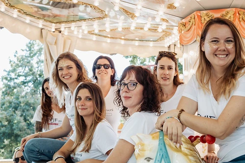 groupe de femmes souriantes en t-shirts blancs profitant d’un tour de manège décoré et lumineux à Dijon.