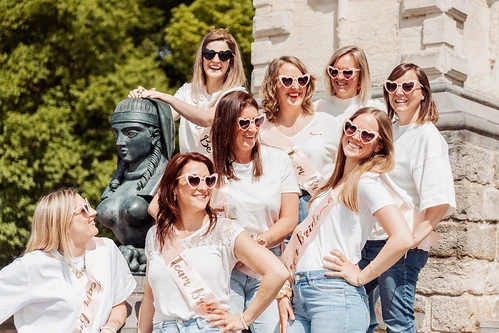 groupe de femmes souriantes pendant un evjf a lille posant pres d une statue en plein soleil