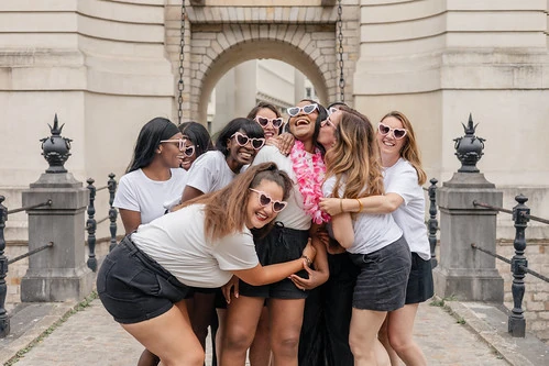 groupe de femmes riant ensemble pendant un evjf a lille devant une arche monumentale