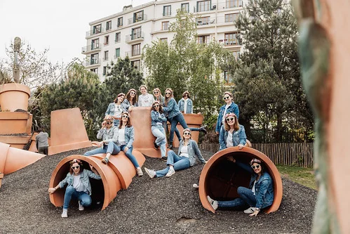 groupe de femmes en jean posant sur des sculptures geantes de pots de fleurs 