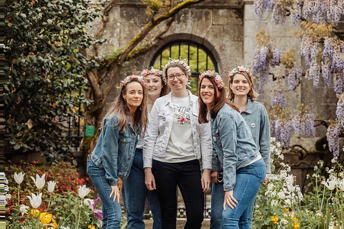 groupe de femmes portant des couronnes de fleurs posant dans un jardin fleuri a nantes pendant un evjf
