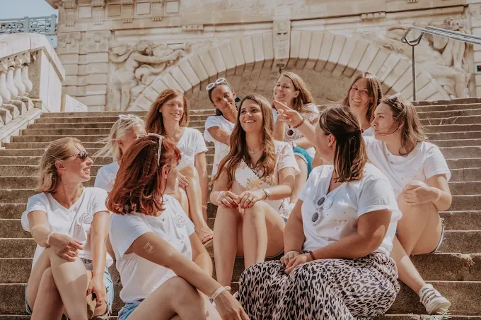Que visiter à Paris pendant un EVJF : amies assises sur des escaliers historiques, rires au soleil, ambiance complice.