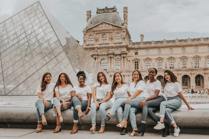 Groupe de femmes posant devant la pyramide du Louvre à Paris pendant un EVJF, ambiance élégante et joyeuse.