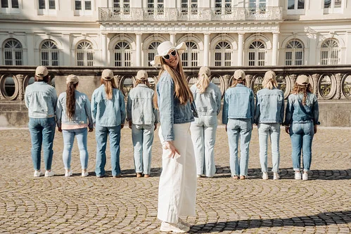 Groupe de femmes en jean posant pour un shooting photo EVJF à Bruxelles, avec la mariée habillée en blanc devant un bâtiment historique.