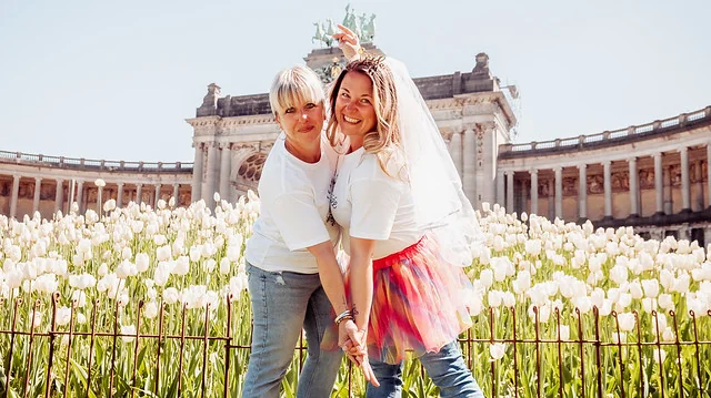 Deux femmes souriantes posant dans un champ de tulipes lors d’un shooting photo EVJF à Bruxelles, devant un monument historique.