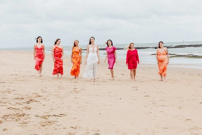groupe de femmes marchant sur la plage en robe colorée lors d’un shooting photo evjf à la baule