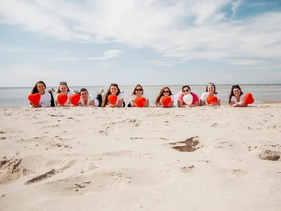 groupe de femmes allongées sur le sable tenant des ballons rouges en forme de cœur